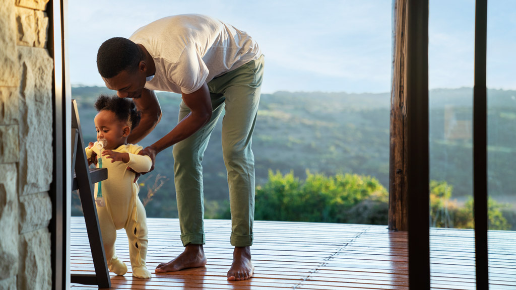 Pai brincando com a filha na varanda de uma casa de campo.