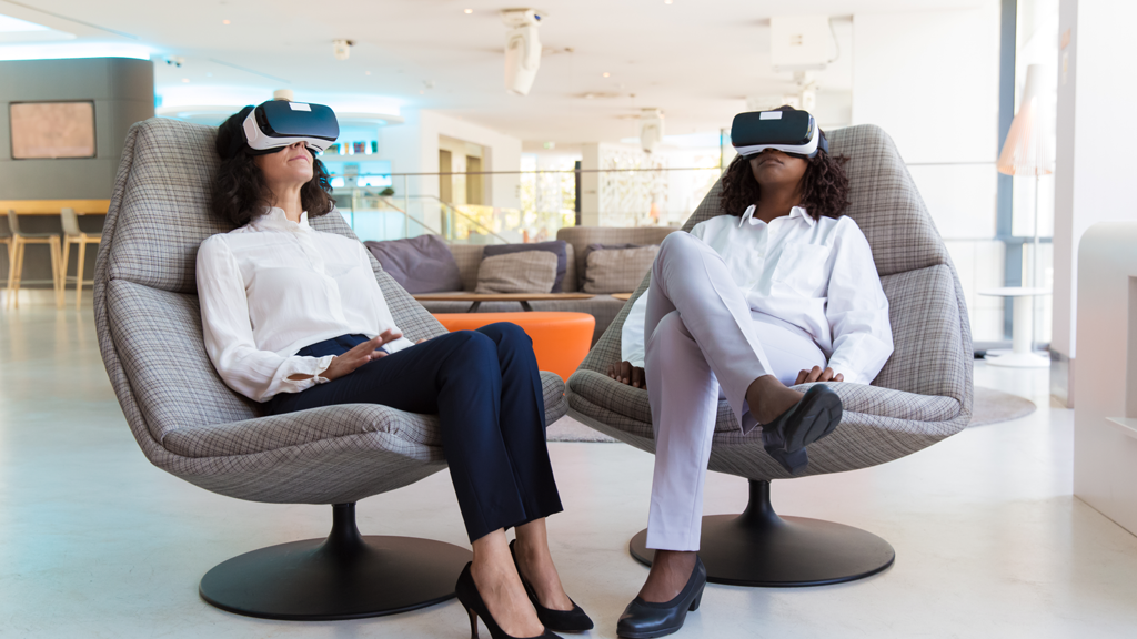 Duas mulheres usando headsets de realidade virtual em um escritório.