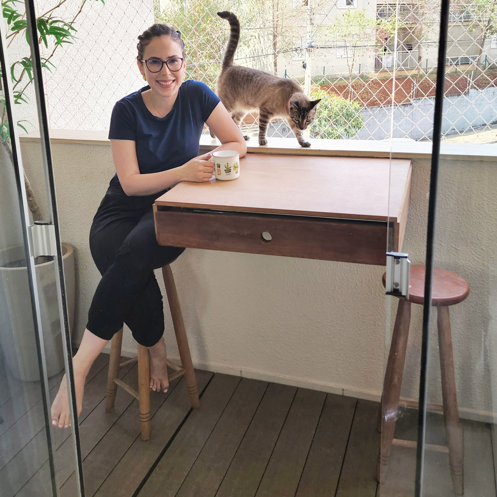 Uma mulher sentada em um banco ao lado de uma mesa junto a seu gato