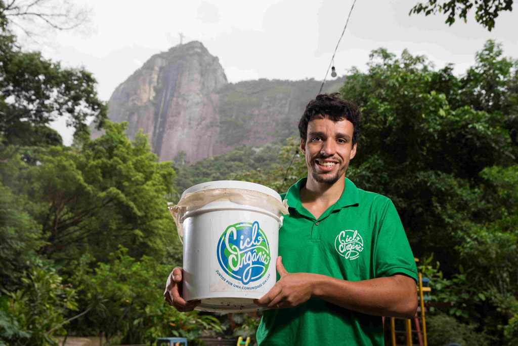Um homem segurando um balde de compostagem.