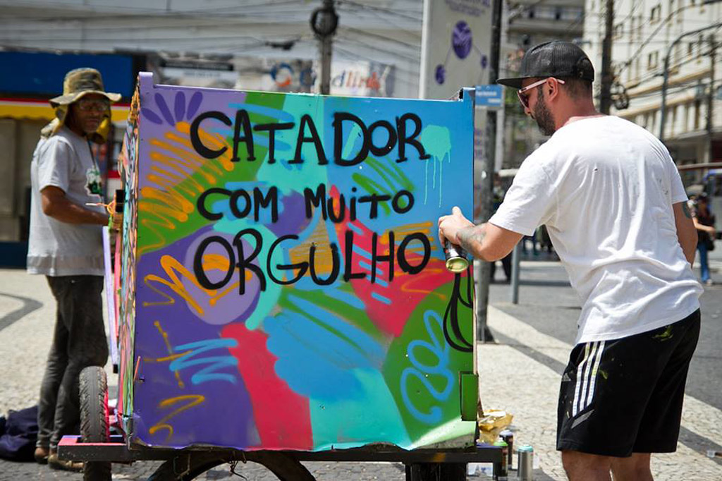 Um homem pinta uma placa com as palavras: "Catador com muito orgulho"