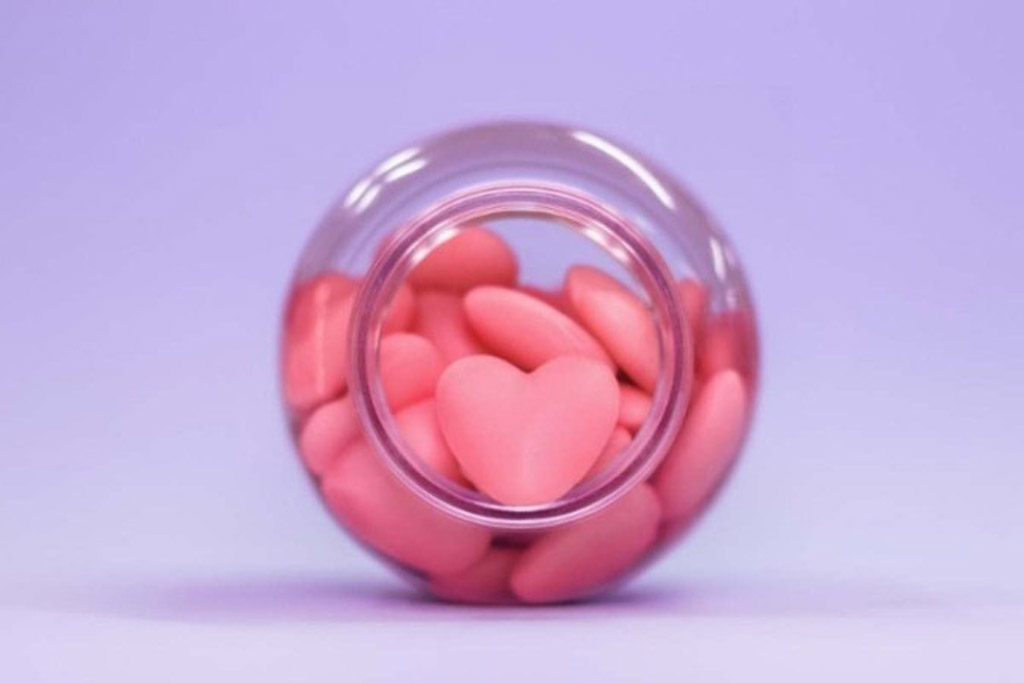 Um pote com suplementos para crescimento de cabelo em formato de coração.