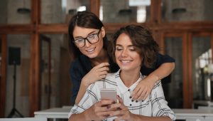 Duas mulheres sorridentes olhando para um celular