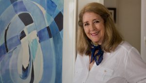 Uma pintora ao lado de um quadro abstrato